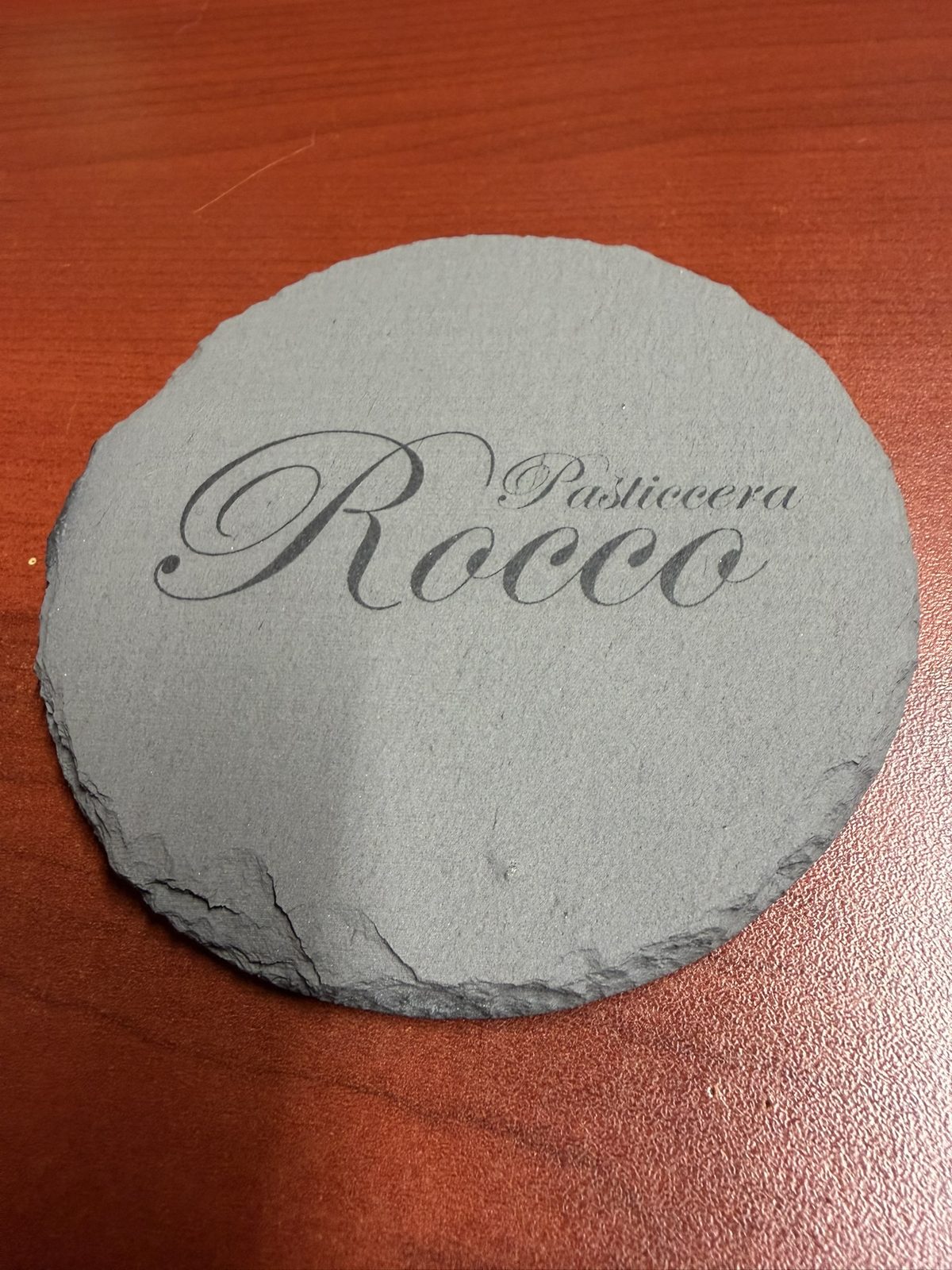 Round slate coaster engraved Pasticcera Rocco in script