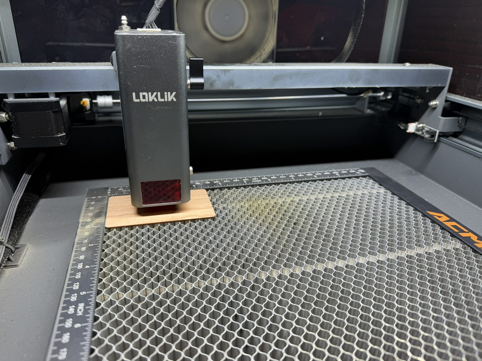 LOKLIK laser head over a small hardwood card on the honeycomb bed